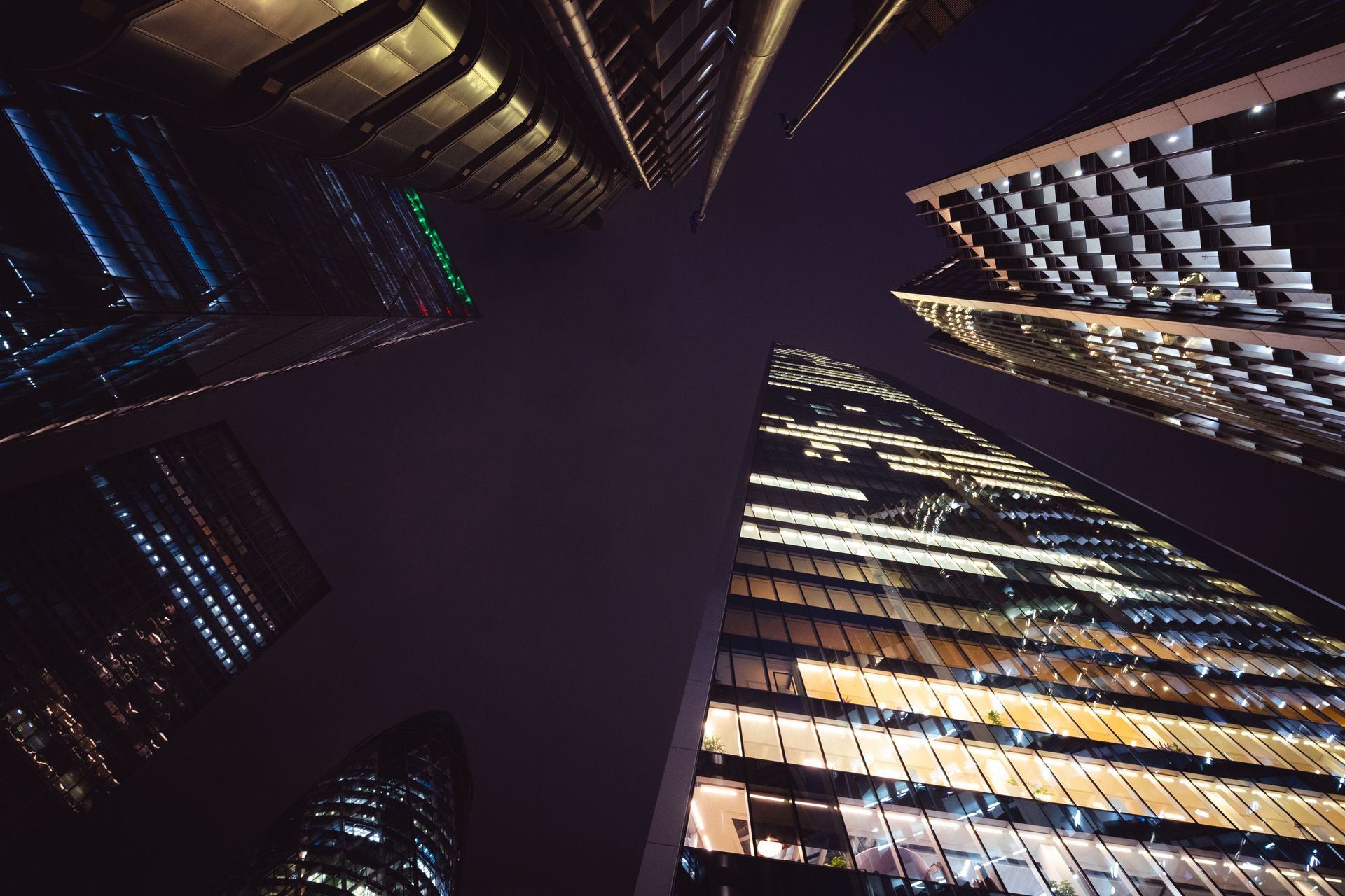 A striking upward view of illuminated modern skyscrapers at night in London, England.